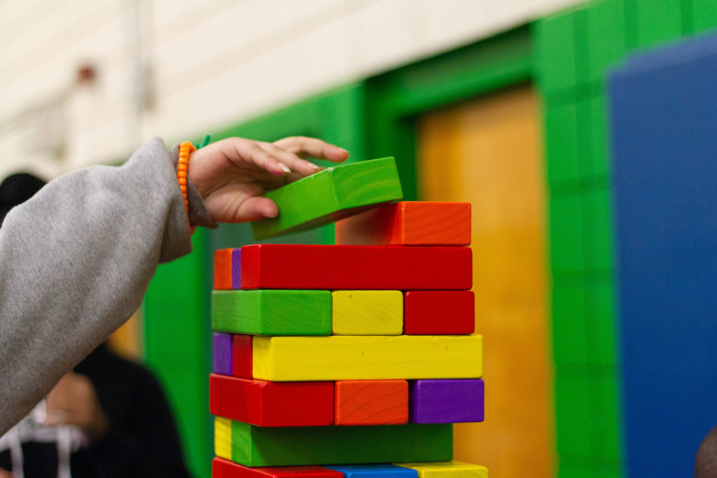 A person with autism engaging in occupational therapy, holding a stack of colorful blocks.